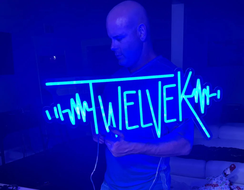 DJ 12K behind a blue neon TWELVEK sign