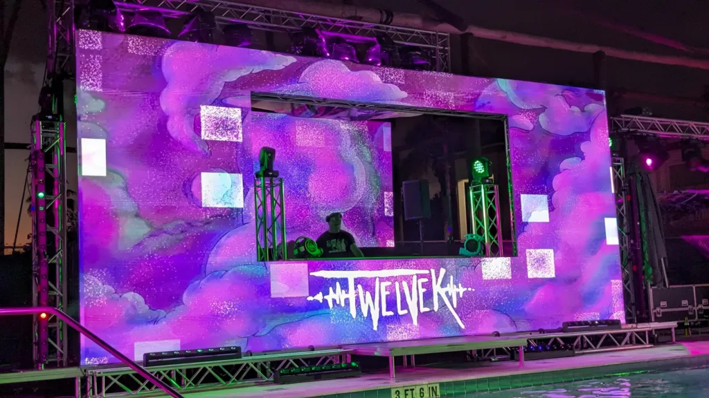 Outdoor stage with a purple LED backdrop showing the TWELVEK logo